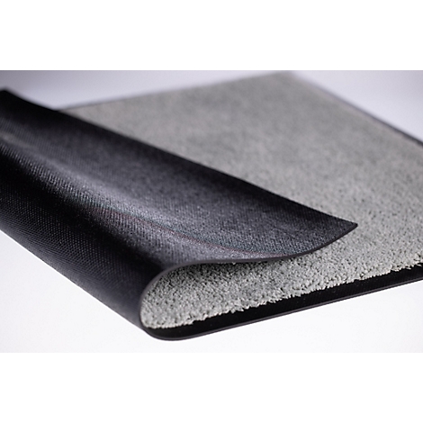 Een tapijt met een grijze pooloppervlakte en een zwarte, antislip rubberen achterkant, lichtjes omgeklapt.