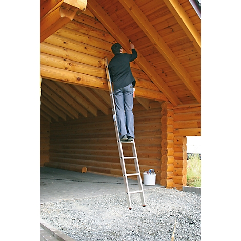 Personne sur une échelle peignant le plafond en bois dans une maison en bois.