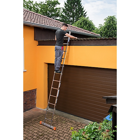 Homme sur une échelle nettoyant la gouttière d'une maison. Mur de la maison jaune et garage marron.
