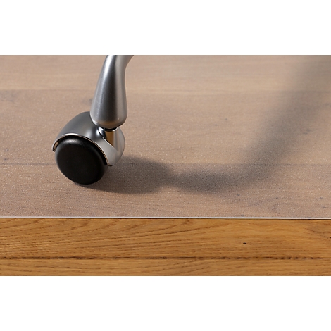 Close-up van een stoelpot op een houten vloer. De zwarte kunststof zwenkwiel en de metalen poot werpen schaduwen.