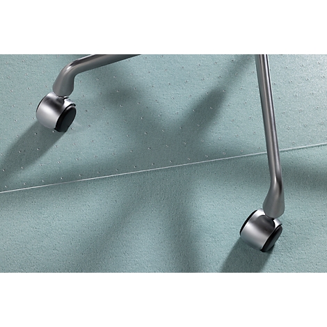 Primer plano de ruedas de silla plateadas sobre una alfombra azul. Las ruedas son de metal y tienen detalles negros.