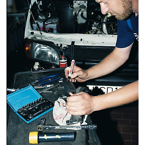 Mechanic working on a car, using a pen. Tools are on the table.