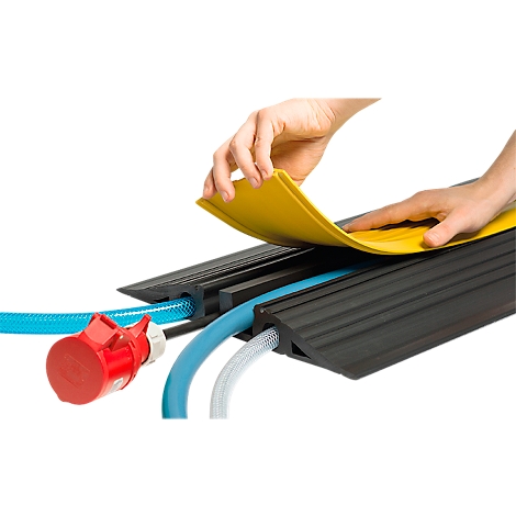Person placing a yellow cover on a black cable bridge. Blue and white cables and a red plug are visible.