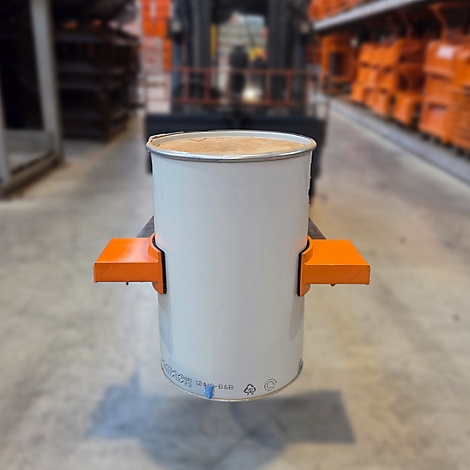 Weißer Fassbehälter wird mit Gabelstapler transportiert. Orangefarbene Halterungen fixieren den Behälter. Lagerhallen-Hintergrund.