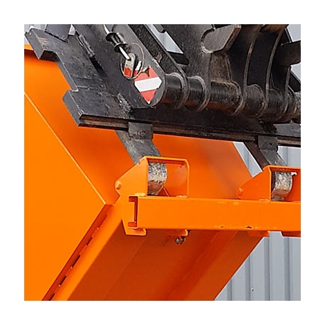 Detailaufnahme einer orangefarbenen Baggerschaufel mit schwarzen Metallteilen, darunter ein rotes und weißes Warnschild.