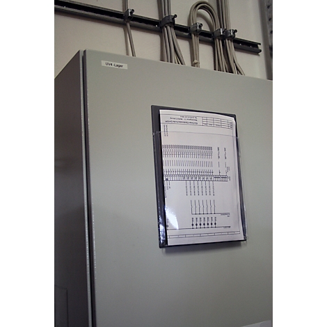 Grey control cabinet, document in clear plastic sleeve. Cables run along the ceiling.