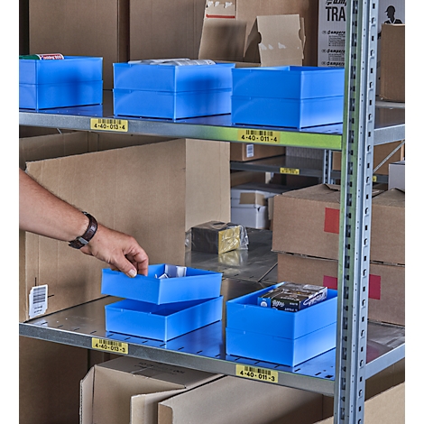 Person placing a blue plastic box on a shelf. Other boxes and cartons are on the shelves. In the background, more shelves can be seen.