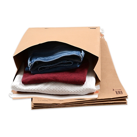 Un jean, un pull rouge et un pull en tricot blanc sont dans une enveloppe d'expédition marron. Sur fond blanc.