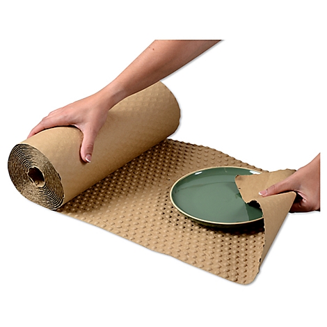 Des mains tiennent un rouleau de papier d'emballage marron et enveloppent une assiette verte.