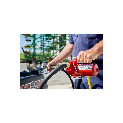 A person holds a red pump connected to a black hose. A green field is visible in the background.