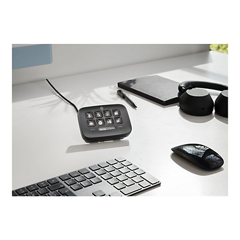 Schwarzes Bedienfeld mit beleuchteten Knöpfen, Kopfhörer, Maus, Tastatur, Notizbuch und Stift auf weißem Tisch.