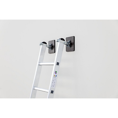 Une échelle en aluminium appuyée contre un mur blanc. Elle est fixée avec deux supports noirs.