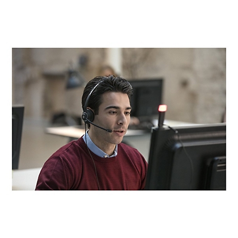 Ein Mann mit Headset sitzt vor einem Computer und spricht.