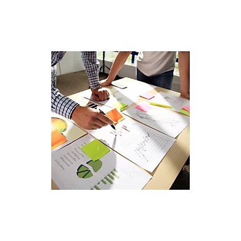 Zwei Personen stehen an einem Tisch und betrachten Diagramme und Notizen. Der eine hält einen Stift.