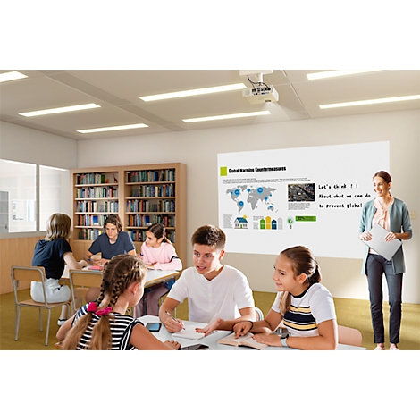 Classroom with students and teacher. A projection shows climate change diagrams. Students discuss at tables.