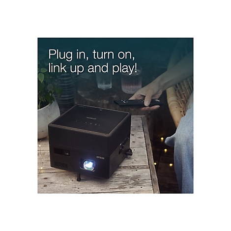 Ein schwarzer Epson-Projektor steht auf einem Holztisch. Darüber steht in weißer Schrift: „Plug in, turn on, link up and play!“. Eine Person hält eine Fernbedienung.
