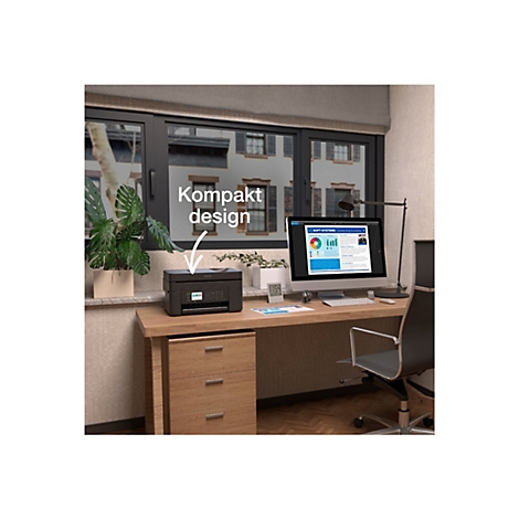 Schwarzer Drucker auf einem Schreibtisch. Auf dem Monitor Diagramme. Das Fenster zeigt ein Wohnhaus. Der Text sagt: Kompaktes Design.