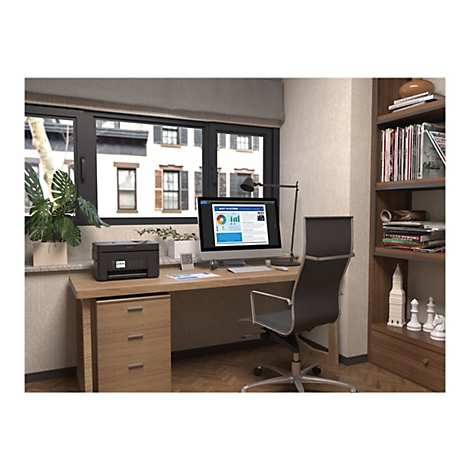 BÃ¼ro-Szene mit einem Schreibtisch, Drucker und Monitor. DrauÃŸen sind GebÃ¤ude zu sehen.