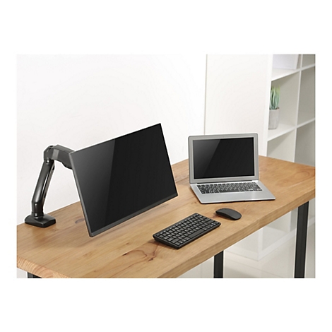 Ein schwarzer Bildschirm an einem Monitorarm steht neben einem Laptop, einer Tastatur und einer Maus auf einem Holzschreibtisch.