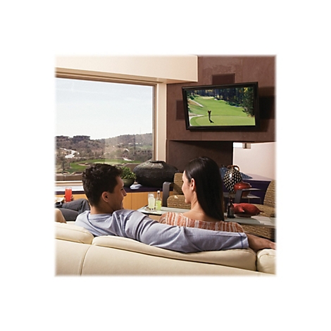 Paar entspannt auf Sofa vor Fernseher. Blick aus Fenster in grÃ¼ne Landschaft. Fernsehbild zeigt Golfer.