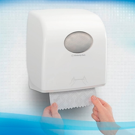 Distributeur d'essuie-mains en papier blanc sur le mur. Mains sortant des essuie-mains en papier.