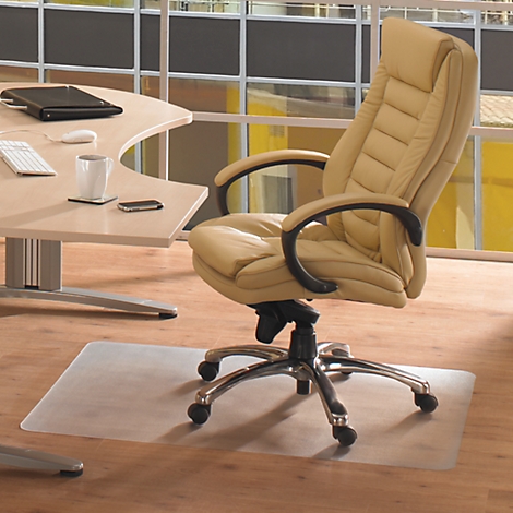 Silla de oficina y mesa con accesorios sobre suelo de madera clara. Una alfombra protectora transparente está delante de la silla.