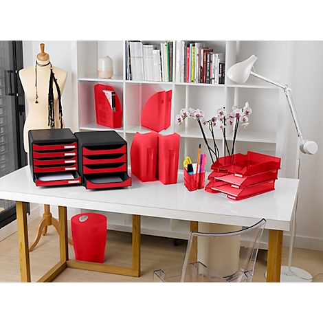 Bürotisch mit roten Büroaccessoires: Ablagen, Ordner, Papierkörbe. Hintergrung: weisses Regal mit Büchern, eine Schaufensterpuppe.