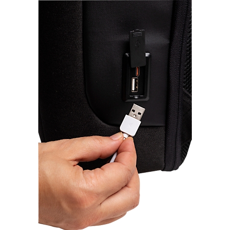 Nahaufnahme: Hand steckt weißen USB-Stecker in schwarzen Rucksack. USB-Anschluss.