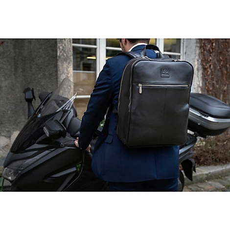 Ein Mann im Anzug mit einem schwarzen Lederrucksack steht neben einem Motorroller.