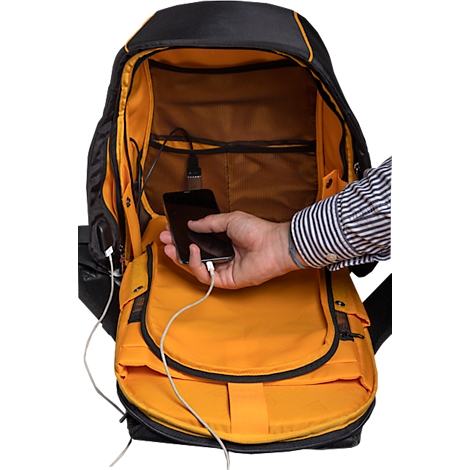 Ein Mann hält sein Handy in der Hand, während es über ein Kabel mit einem Rucksack verbunden ist. Der Rucksack hat eine gelbe Innenseite.