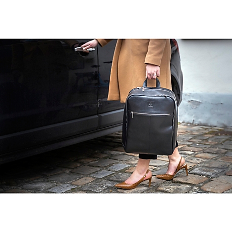 Une femme monte dans une voiture avec un sac à dos noir. Elle porte un manteau beige et des chaussures marron.
