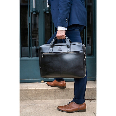 Un homme en costume tient une serviette noire. Il monte les escaliers. Chaussures en cuir marron.
