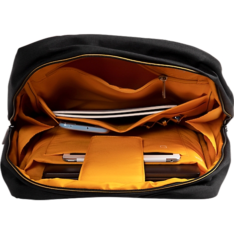 Schwarzer Rucksack mit gelbem Innenfutter. Innen befinden sich ein Laptop, ein Tablet, ein Handy, Kopfhörer und andere Gegenstände.