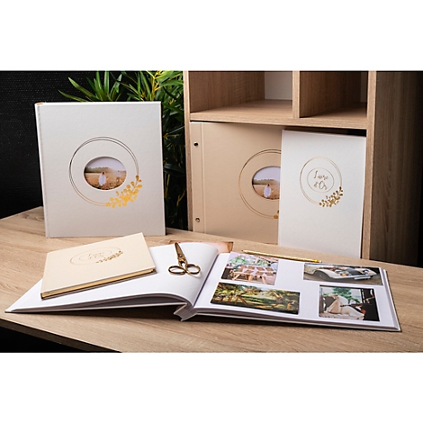 Hochzeitsalben in verschiedenen Größen, geöffnet und geschlossen. Im Hintergrund ein Regal, auf dem weitere Alben stehen. Auf dem offenen Album Fotos.