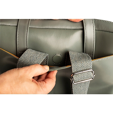 Nahaufnahme einer grauen Handtasche. Der Schulterriemen wird verstellt.