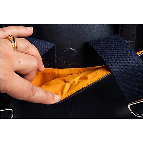 Nahaufnahme einer Hand, die in die gelbe Innentasche eines dunkelblauen Rucksacks greift.