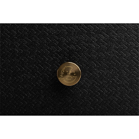 Detailopname: Gouden knop met logo op zwarte, getextureerde achtergrond.