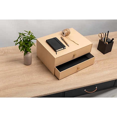 Beigefarbene Schubladenkiste, eine Schublade geöffnet, auf einem Holzschreibtisch. Drauf: Notizbuch, Stift, Garn, Schere, Pflanzen.