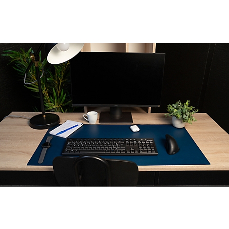 Schreibtisch mit Monitor, Tastatur und Accessoires. Blaue Tischunterlage, eine Uhr und eine Kaffeetasse.