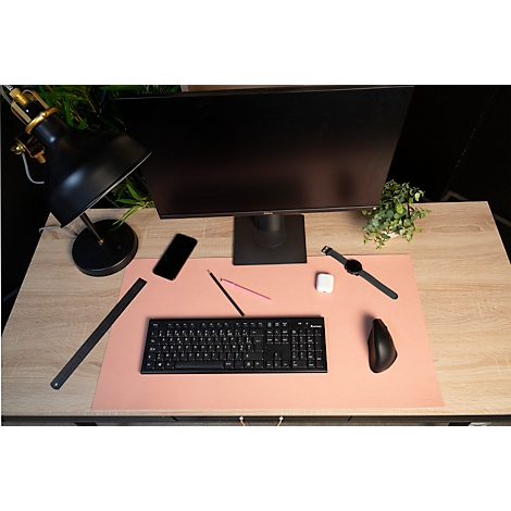 Schreibtisch mit Monitor, Tastatur, Uhr, Handy, Lampe und Maus. Rosa Matte, helles Holz. Alles ist ordentlich angeordnet.