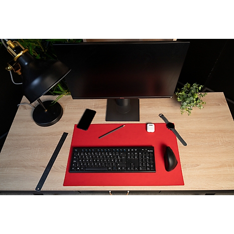 Schreibtisch mit Monitor, Tastatur, Maus, Uhr, Handy, Stift, Lampe, Lineal, und Pflanze.