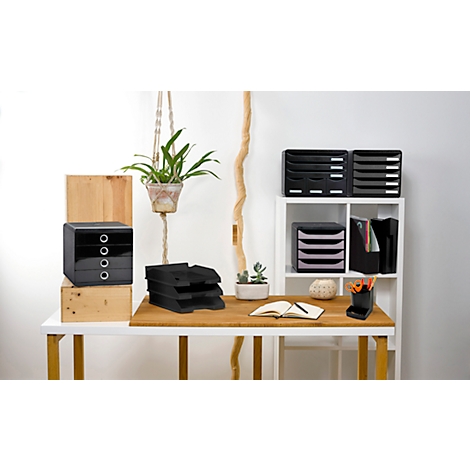 Schreibtisch mit Büroaccessoires: Schubladen, Ablagen, Notizbuch, Pflanze. Holz- und schwarze Elemente dominieren.