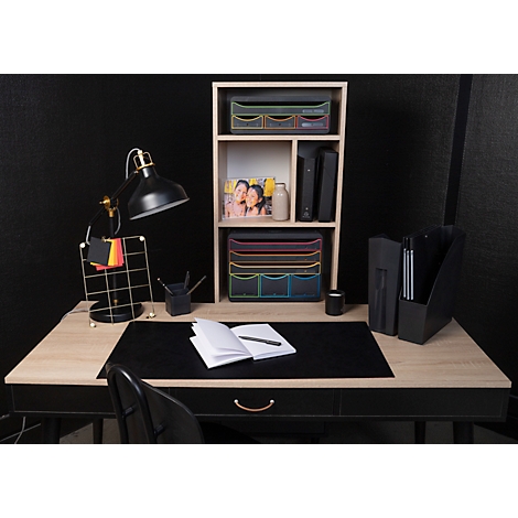 Schreibtisch mit schwarzer Tischplatte, Lampe, Notizblock, Ablagen, Bücher und Accessoires. Schwarzer Hintergrund.
