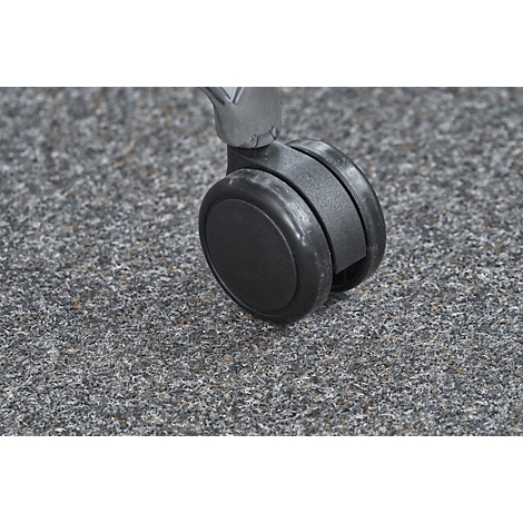 Close-up of a wheelchair wheel on gray carpet. The wheel is black and the holder is chrome-plated.