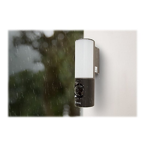 Eine Überwachungskamera an einer Hauswand im Regen. Oben eine weiße Leuchte, unten eine Kamera mit "EZVIZ"-Logo.