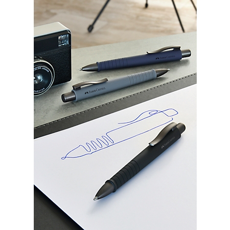 Three pens in blue, grey, and black lie on a surface, with a sketch below.