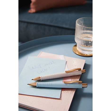 Two pens rest on notepads. A light blue note says: Let's meet later! Next to it is a glass of water.