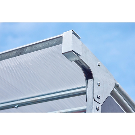 Detailaufnahme einer transparenten Dachkonstruktion aus Metall mit Nietverbindungen. Blauer Himmel im Hintergrund.