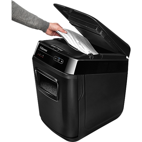 Eine Person legt Papier in einen schwarzen Aktenvernichter der Marke Fellowes ein. Der Deckel ist geöffnet.