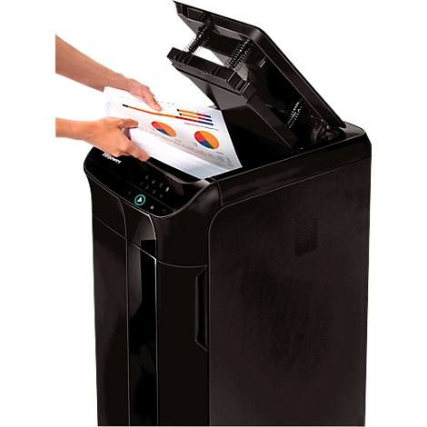 Une personne insère du papier dans un destructeur de documents noir avec le couvercle ouvert. Le papier montre des schémas colorés.